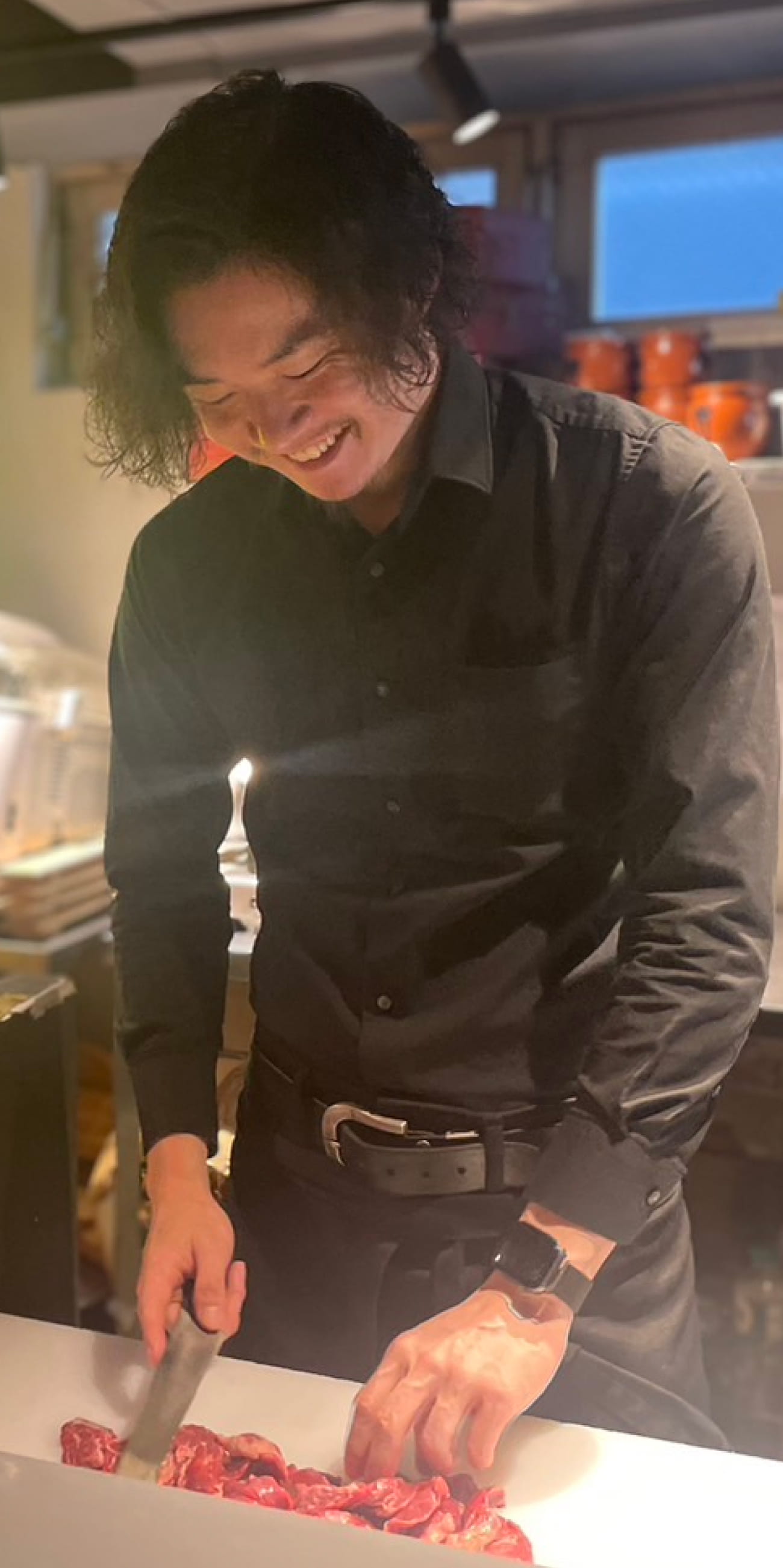 奥野さんが調理場で肉をカットしている様子